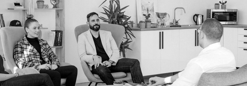 A group hold a discussion while sitting in comfortable chairs